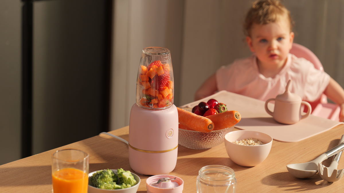 Close-up of the glass cup and stainless steel blades with fresh broccoli and grapes.